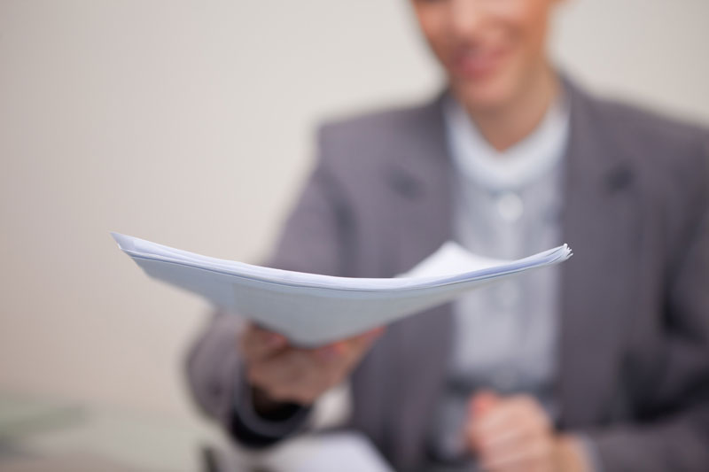 Business man handing papers towards the camera