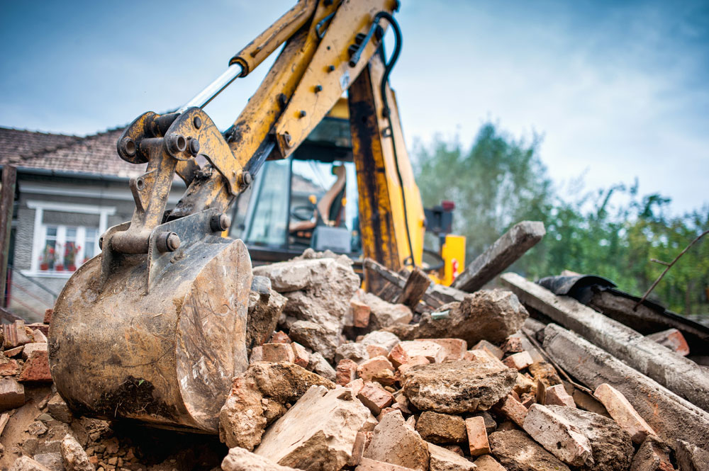 Excavator moving rubble of a demolished house.