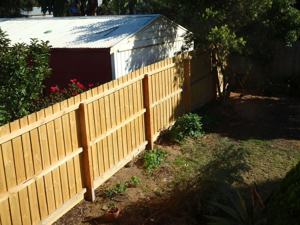 A fence dividing two backyards.