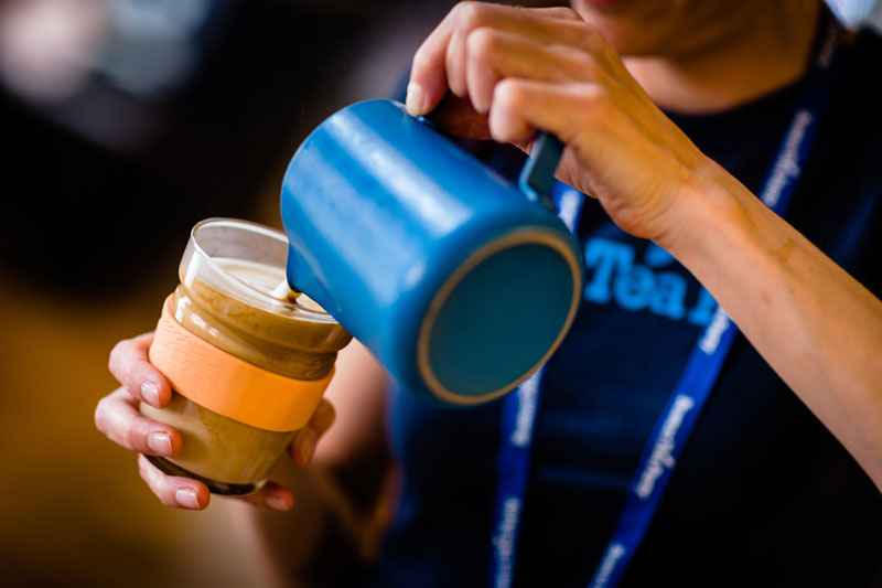 Cafe Barista pouring coffee into reusable coffee cup