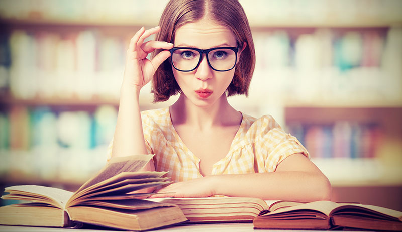 Young woman with book looking over their glasses