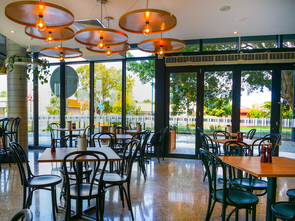 Interior tables with pendant lighting overhead in cafe.