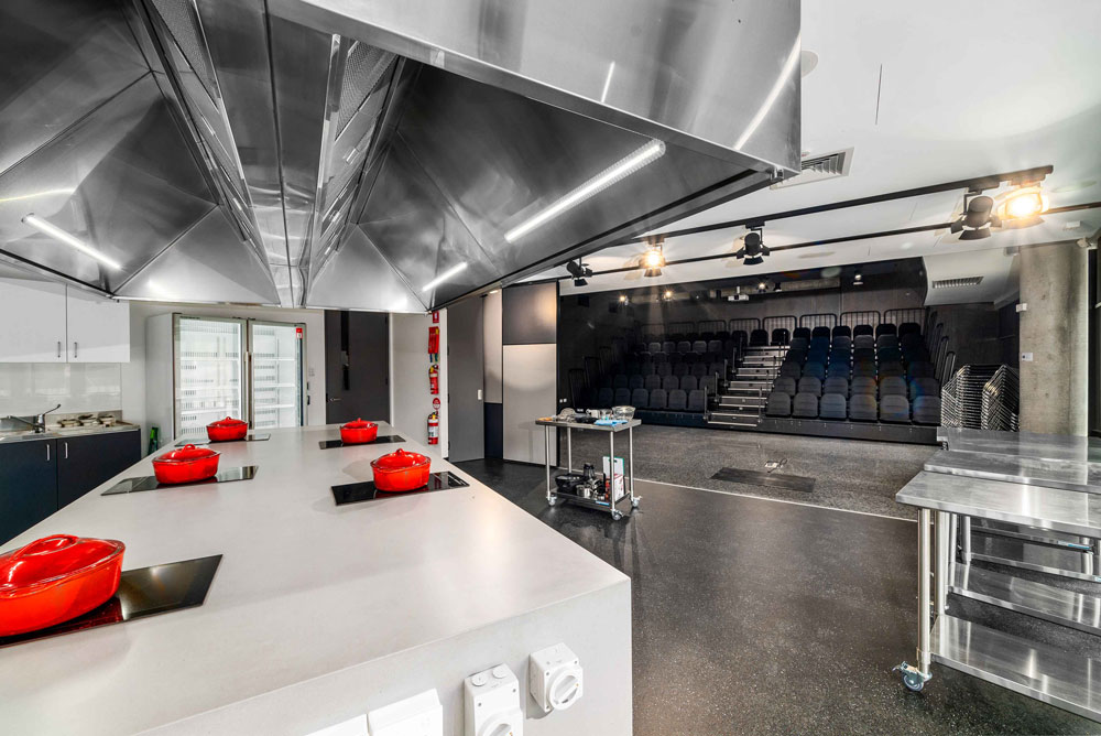 Kitchen with island containing cook tops and red pots.