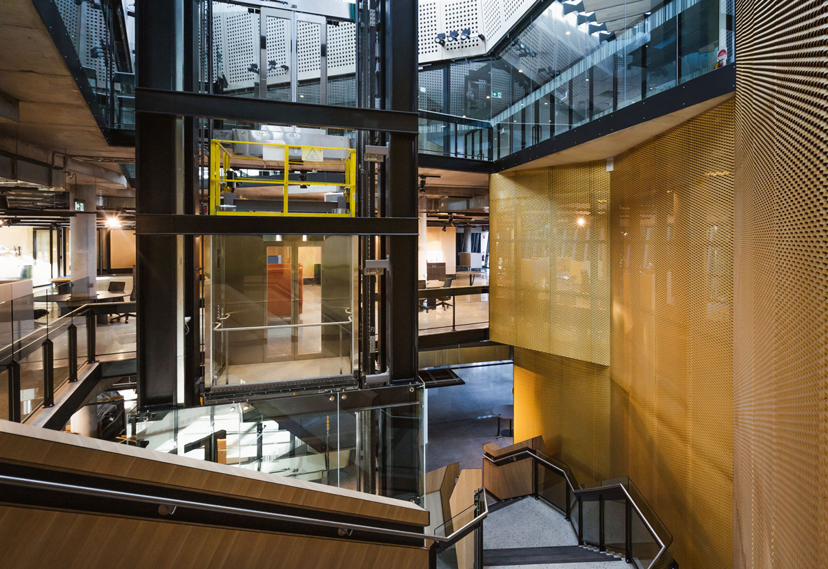 View of steel encased lift and staircase on first floor.