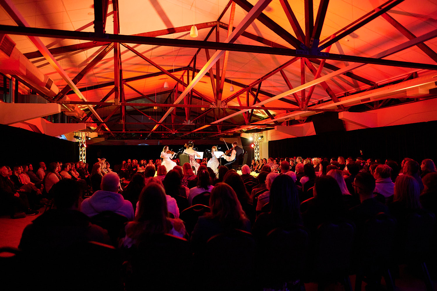 Crowd seated in The Glasshouse with red lighting