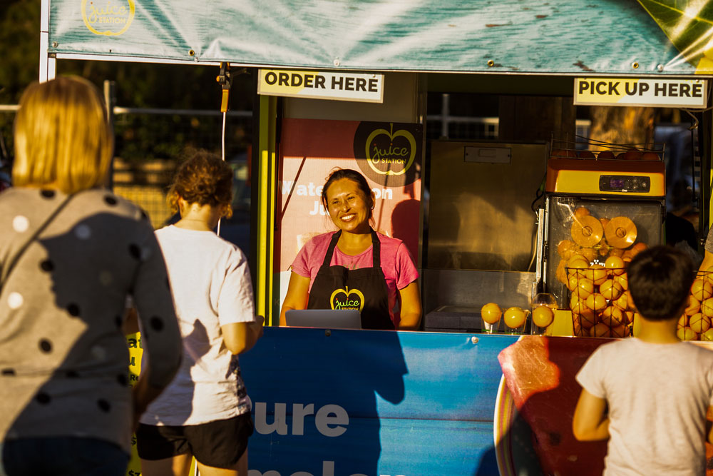 Woman serving orange juice smiling at customers