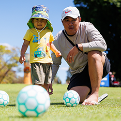 Child with a ball standing next to smiling parent