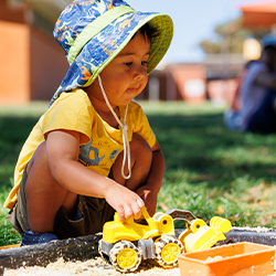 Child playing with a toy truck in an outdoor sandpit