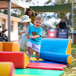 Child with a ball standing next to smiling parent