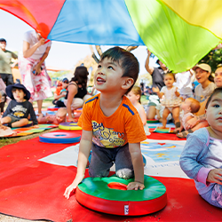 Child with a ball standing next to smiling parent