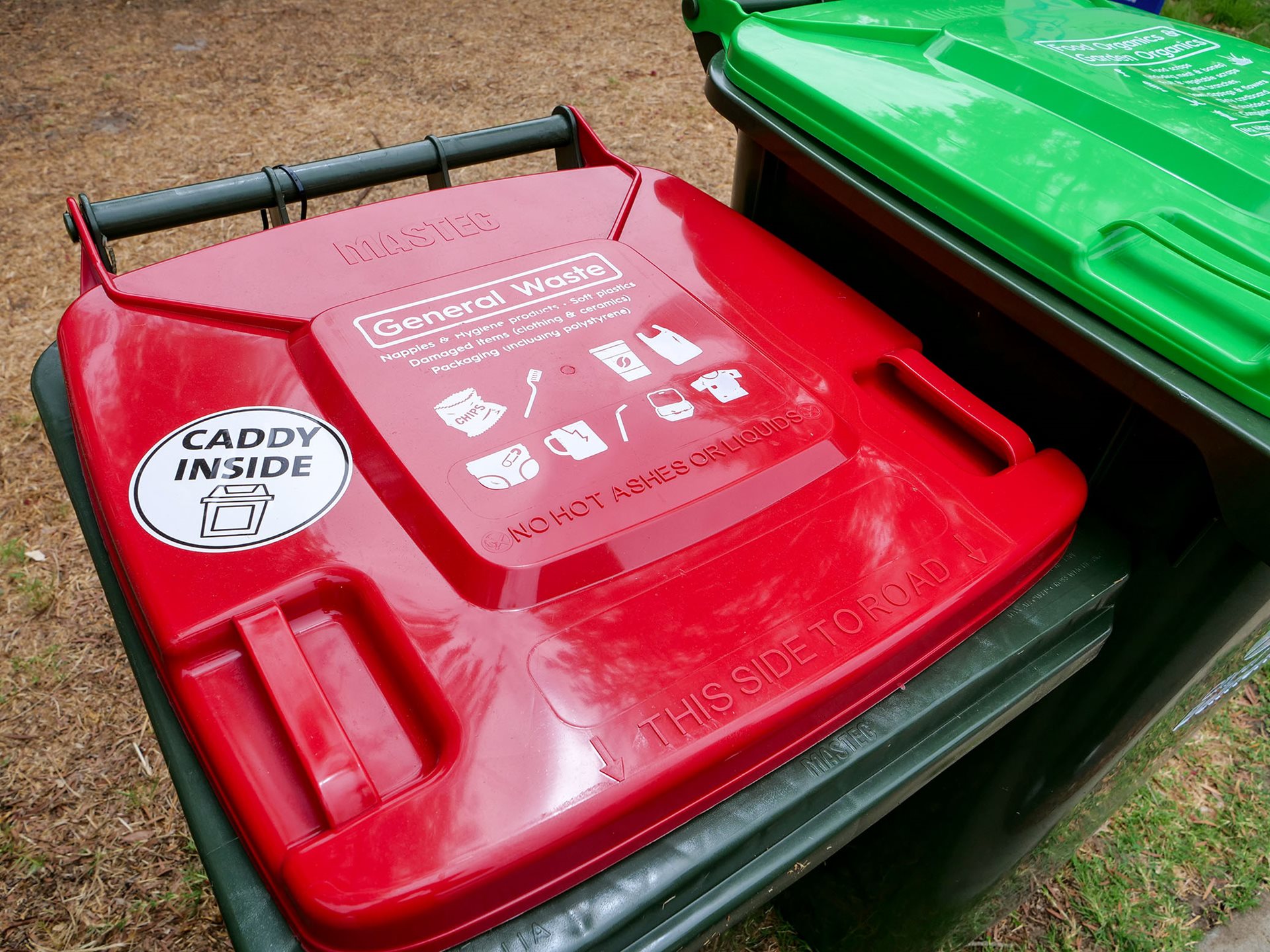 Lid of a red general waste bin with a sticker saying caddy inside