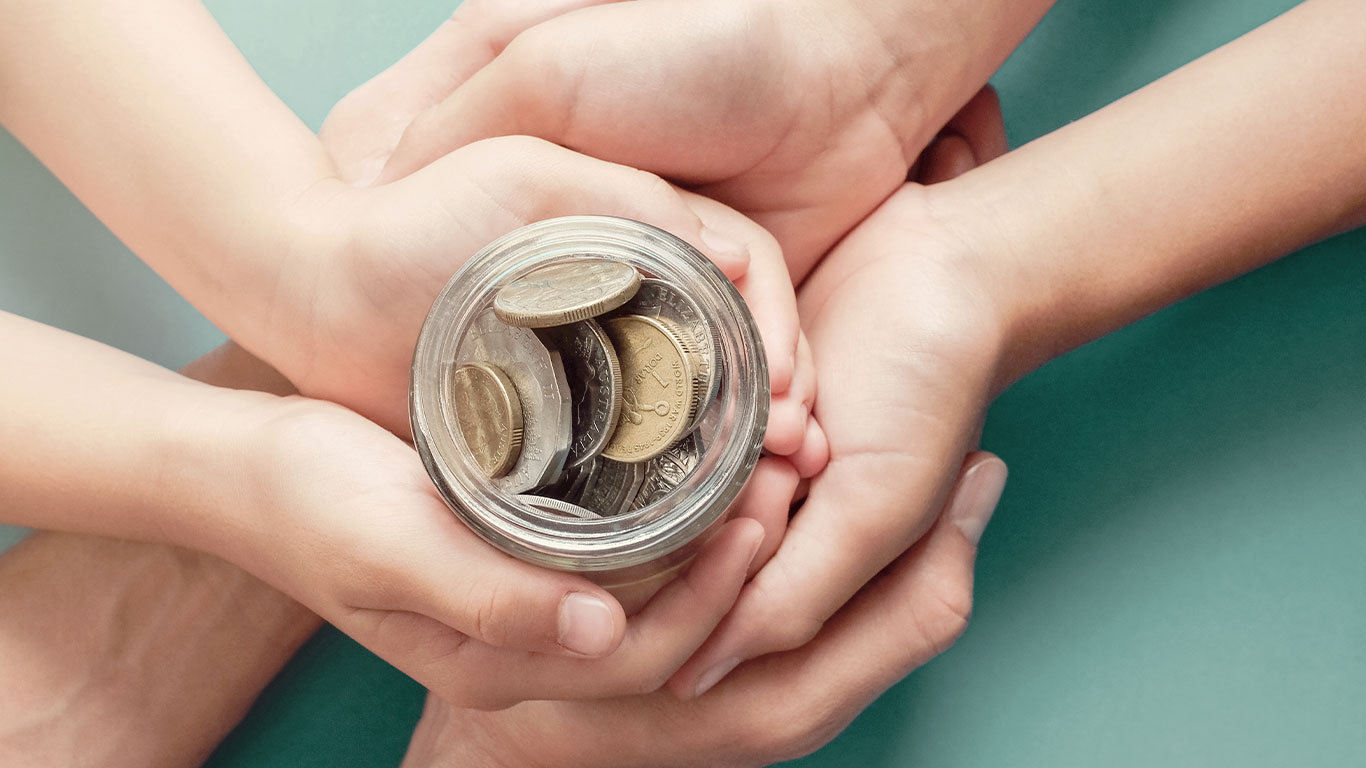 Many hands holding jar of change