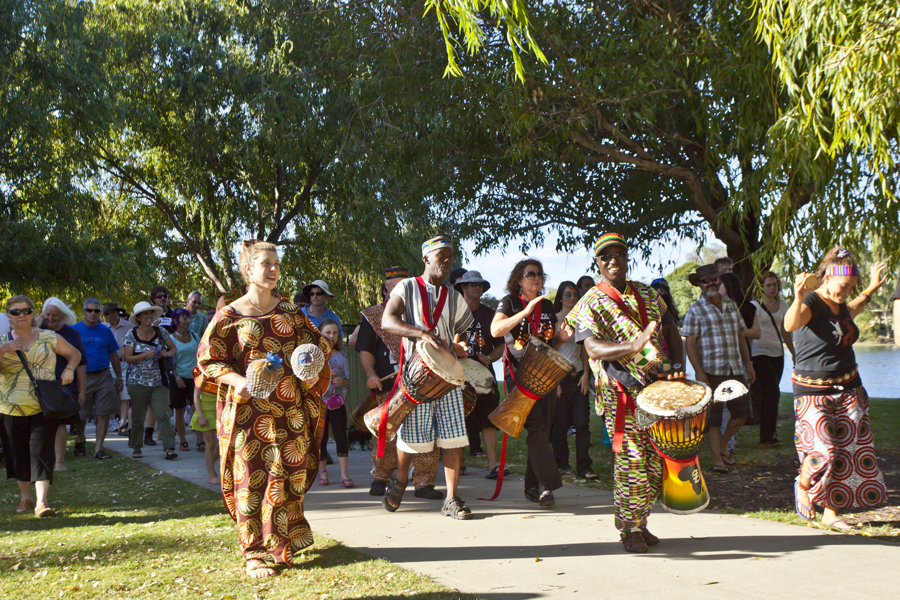 People walking and celebrating whilst drumming and shaking African maracas