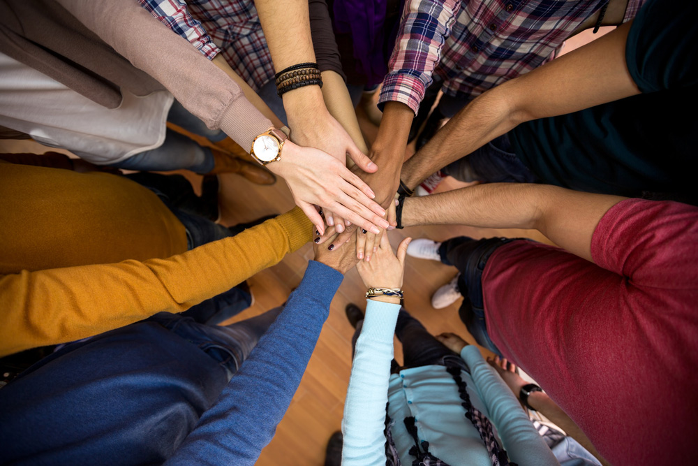 Culturally and linguistically diverse group of people holding hands.