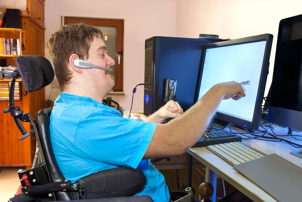 Man in a wheelchair using a computer.