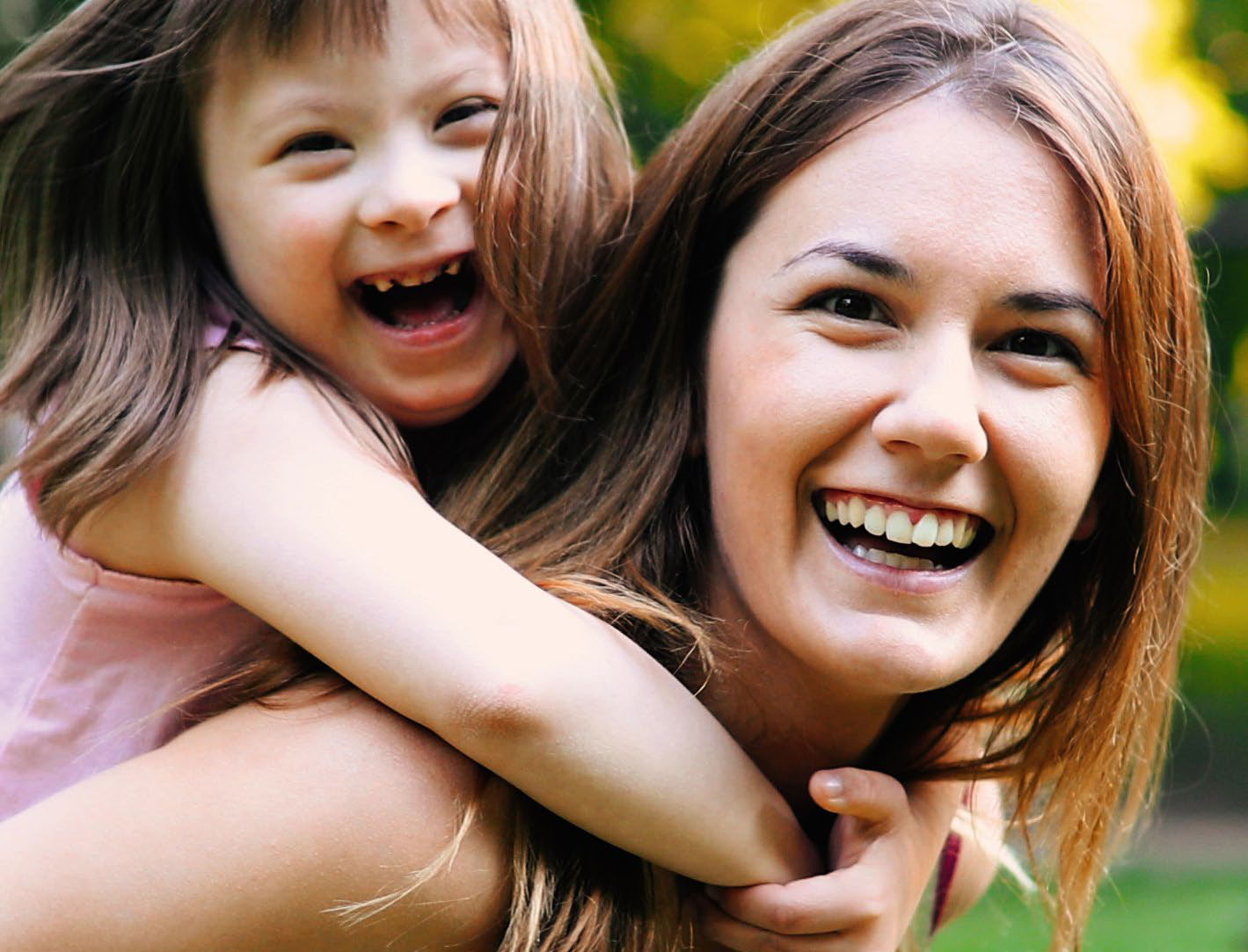 Mother and daughter with down syndrome laughing at the camera.