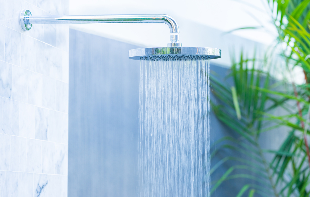 Shower head showering water in a shower.