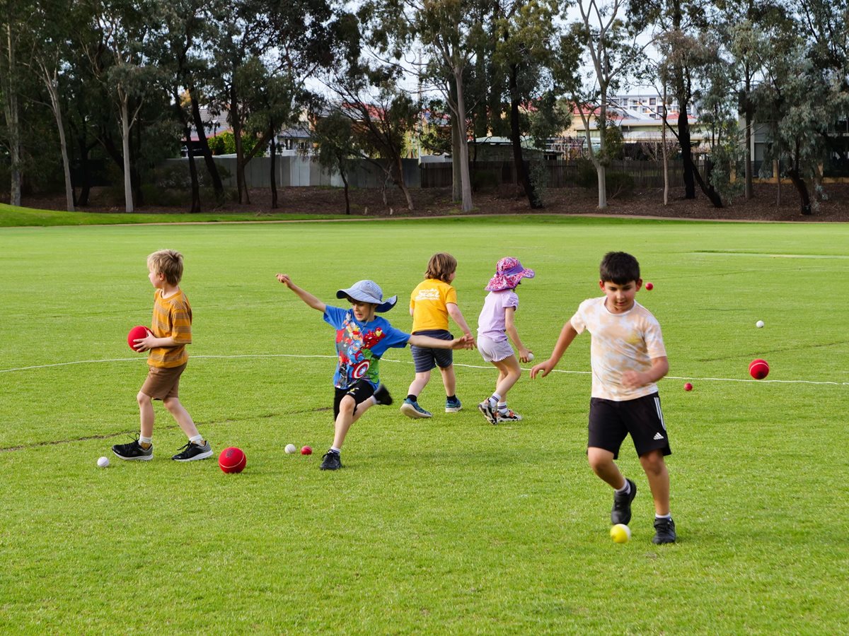 Children playing sport on a green outdoor oval